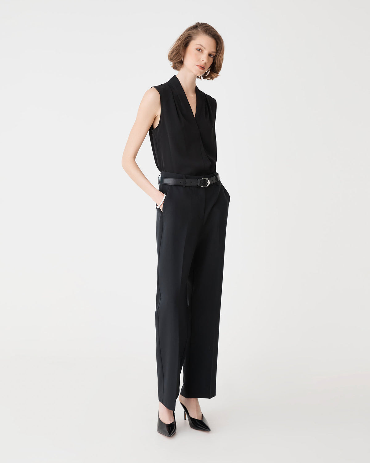 Side view of the black Alivia 2 V-Neck Top worn with black tailored trousers