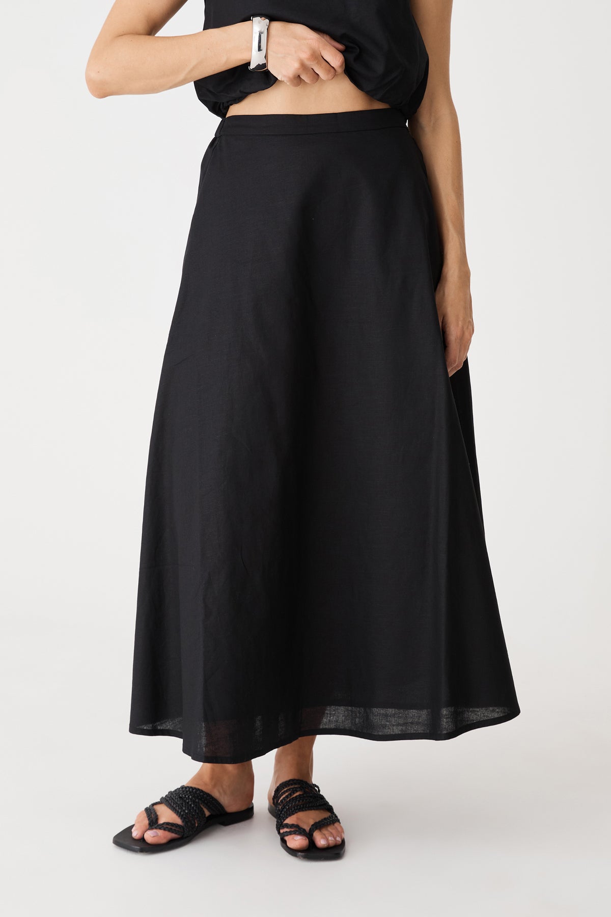 Close-up of the black Kenya Linen Skirt, high waist and A-line flare with hand in side pocket