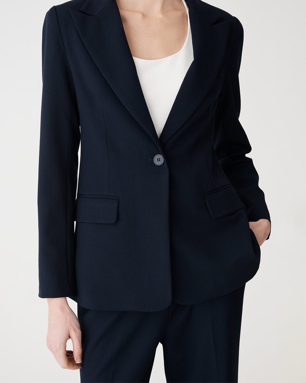 Close-up of the navy blazer's peak lapels, single button and flap hip pockets