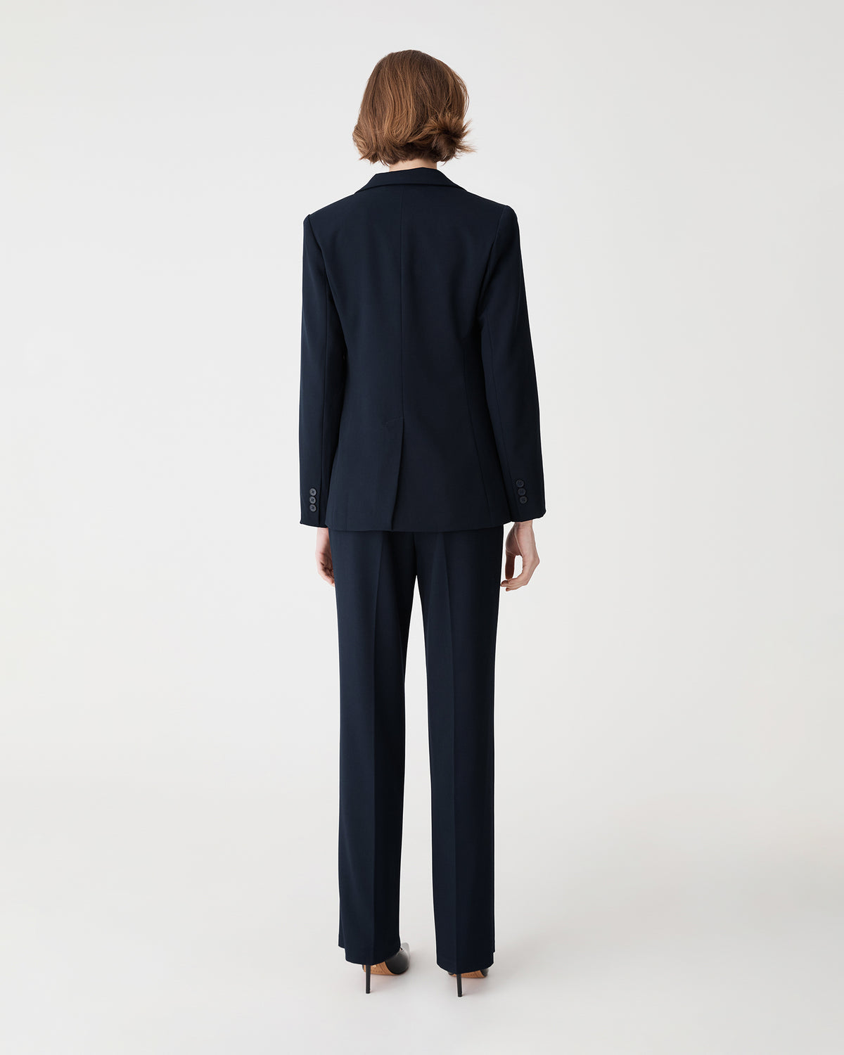Back view of the navy Merid Tailored Pants with faux welt pockets, worn with matching blazer