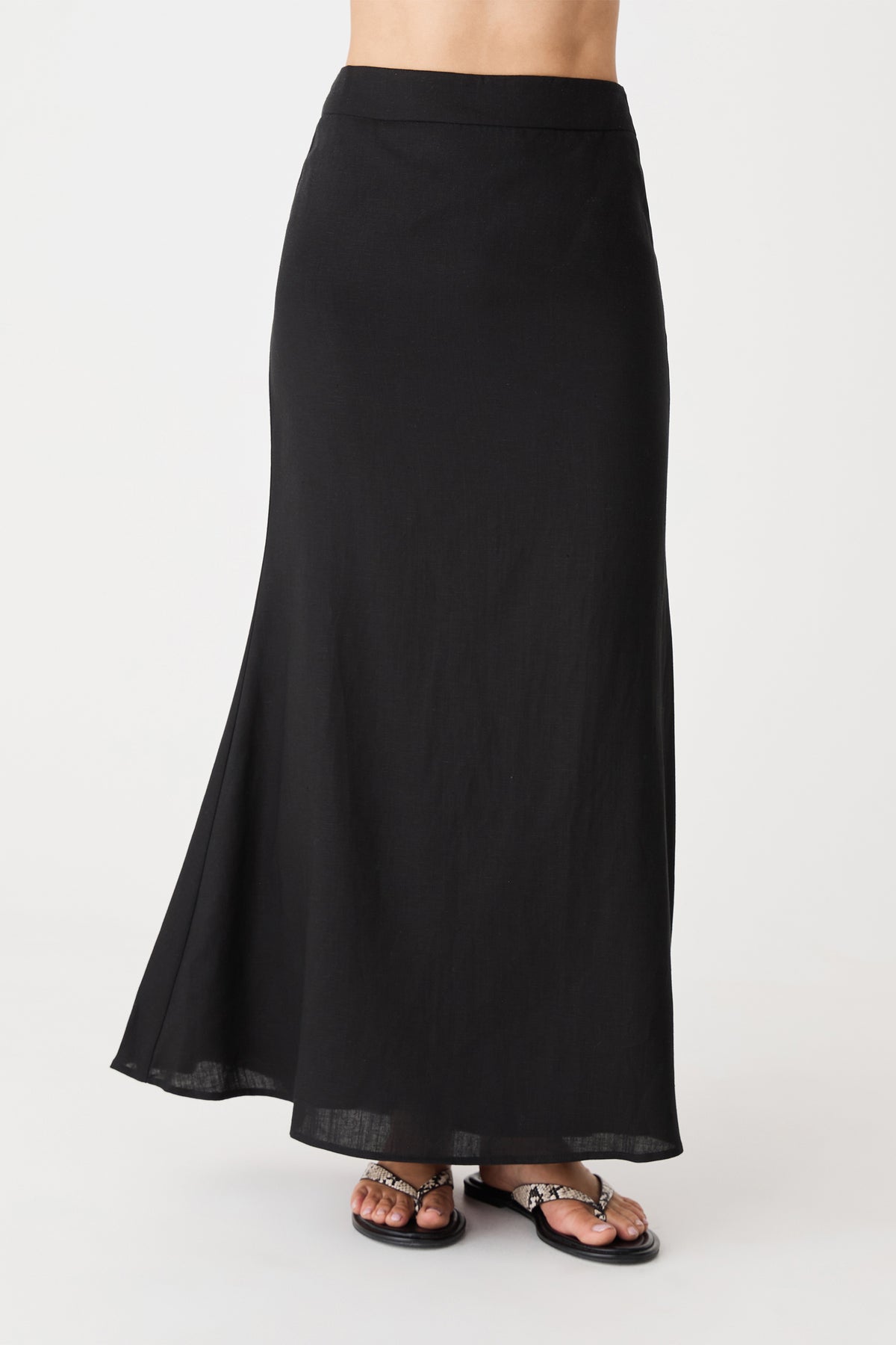 Close-up front view of the black maxi skirt showing high waistband and flute hem