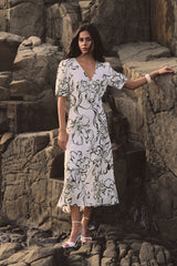 Natalie V-Neck Floral Dress in cream and olive floral print, worn standing on rocks