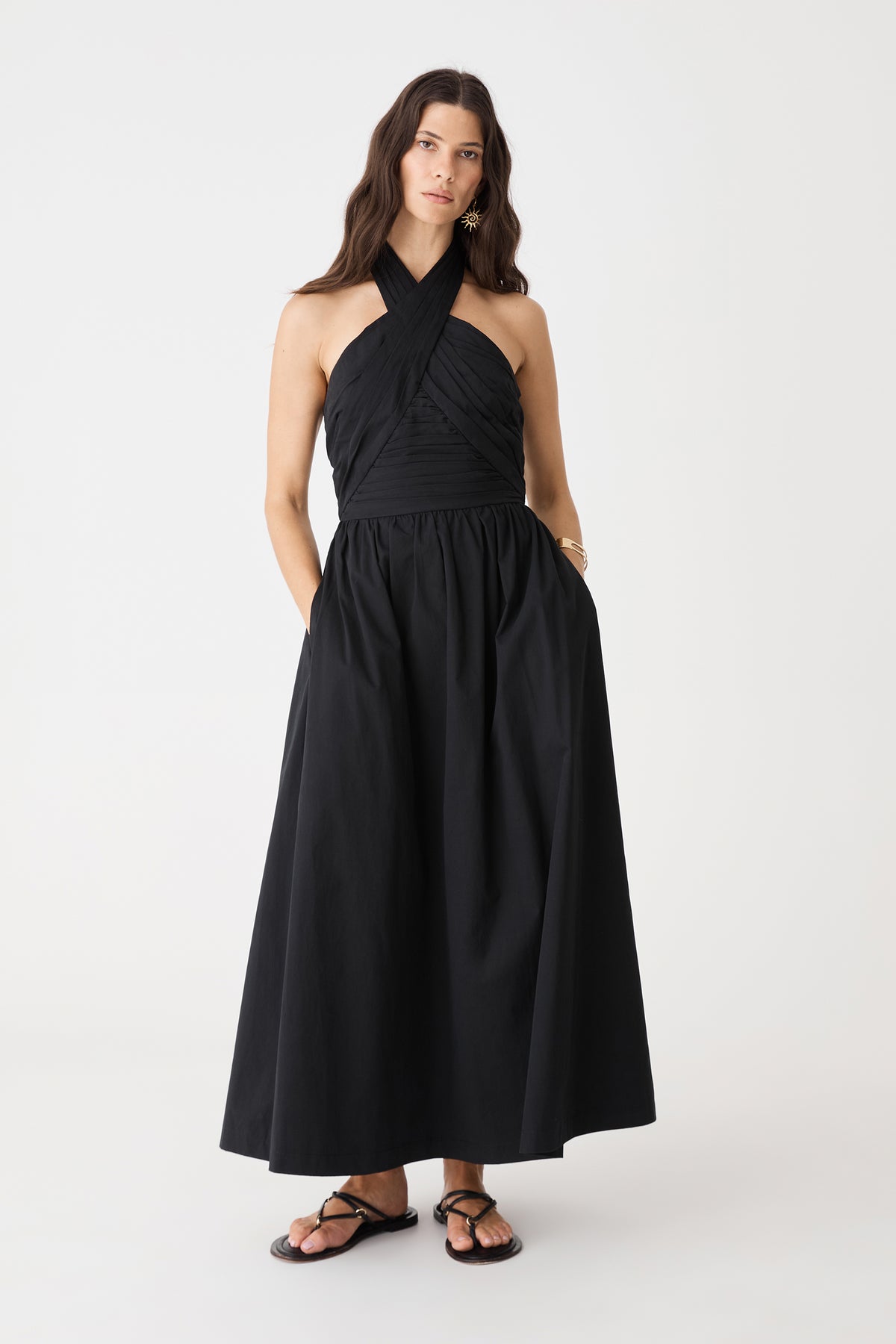 Front view of the black Kayleigh Cotton Halter Dress with hands in the in-seam side pockets