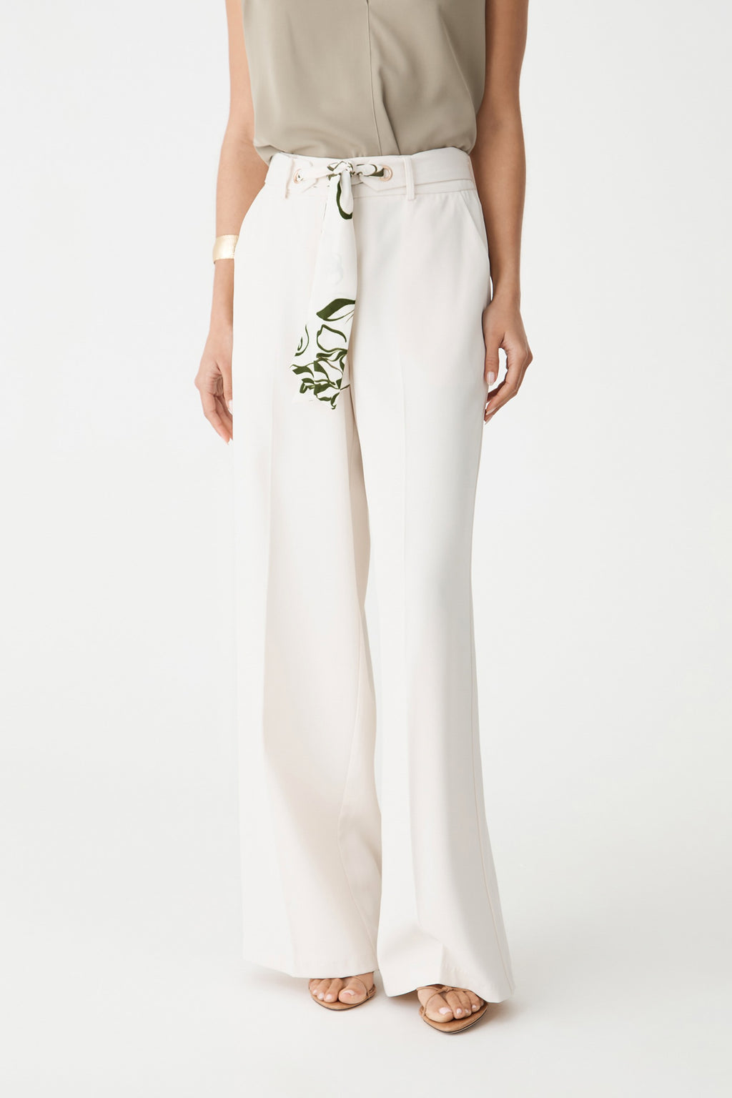 Close-up of the cream wide-leg pants, showing the scarf belt threaded through gold-tone eyelets