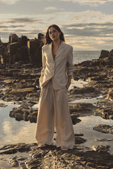 Zoe Elastic Pinstripe Pants in beige pinstripe worn on rocks with a matching blazer, full-length front view