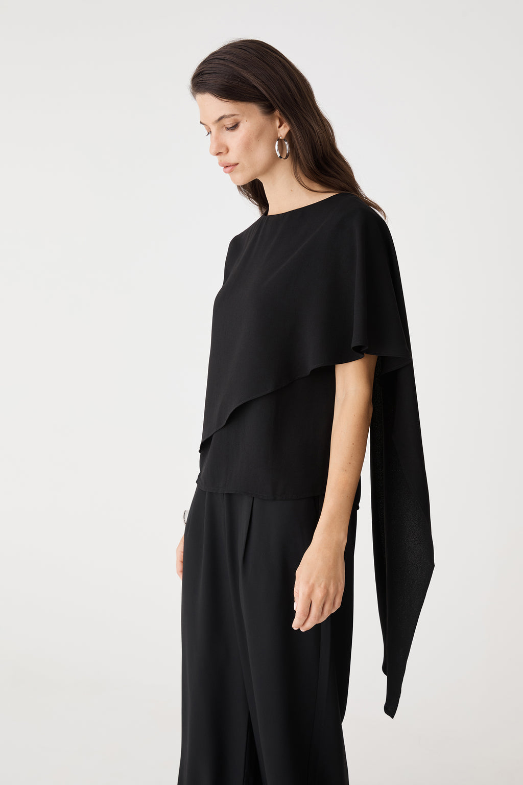 Close-up of the round neckline and draped cape overlay in black