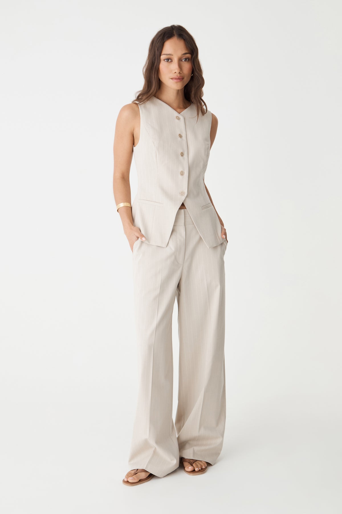 Front view of the beige pinstripe vest showing the inverted V-shaped hem