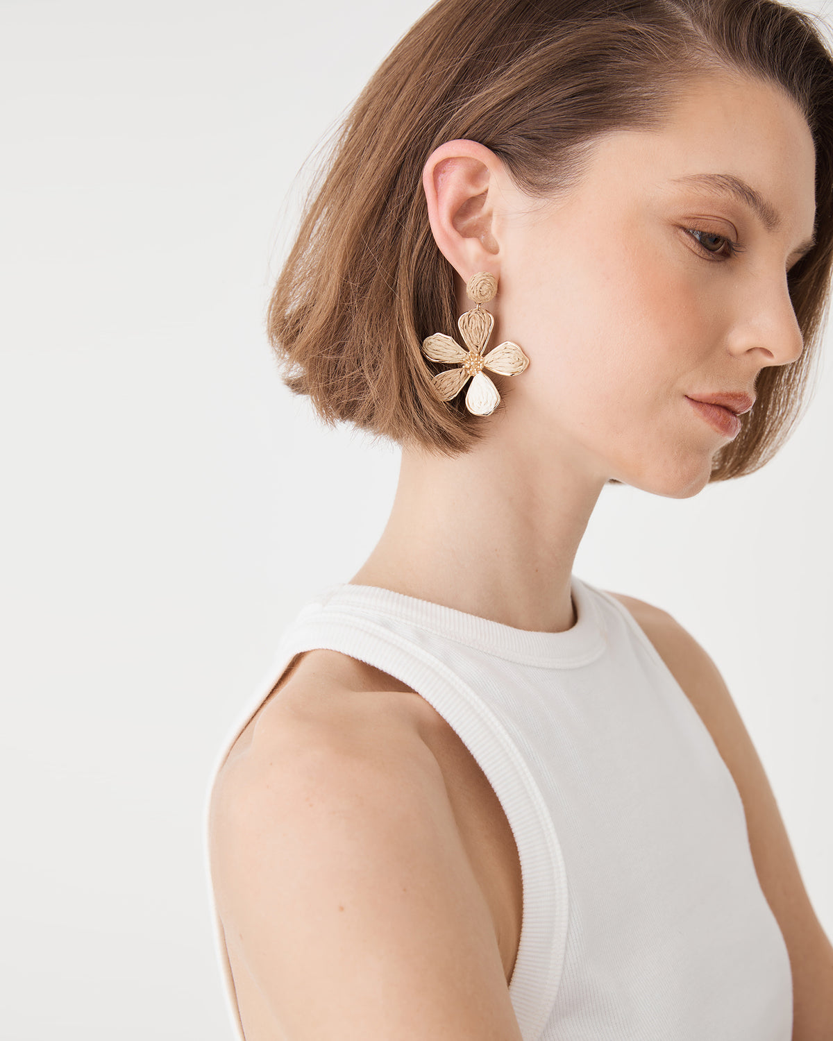 Side profile view of beige raffia petal drop earring with circular stud base