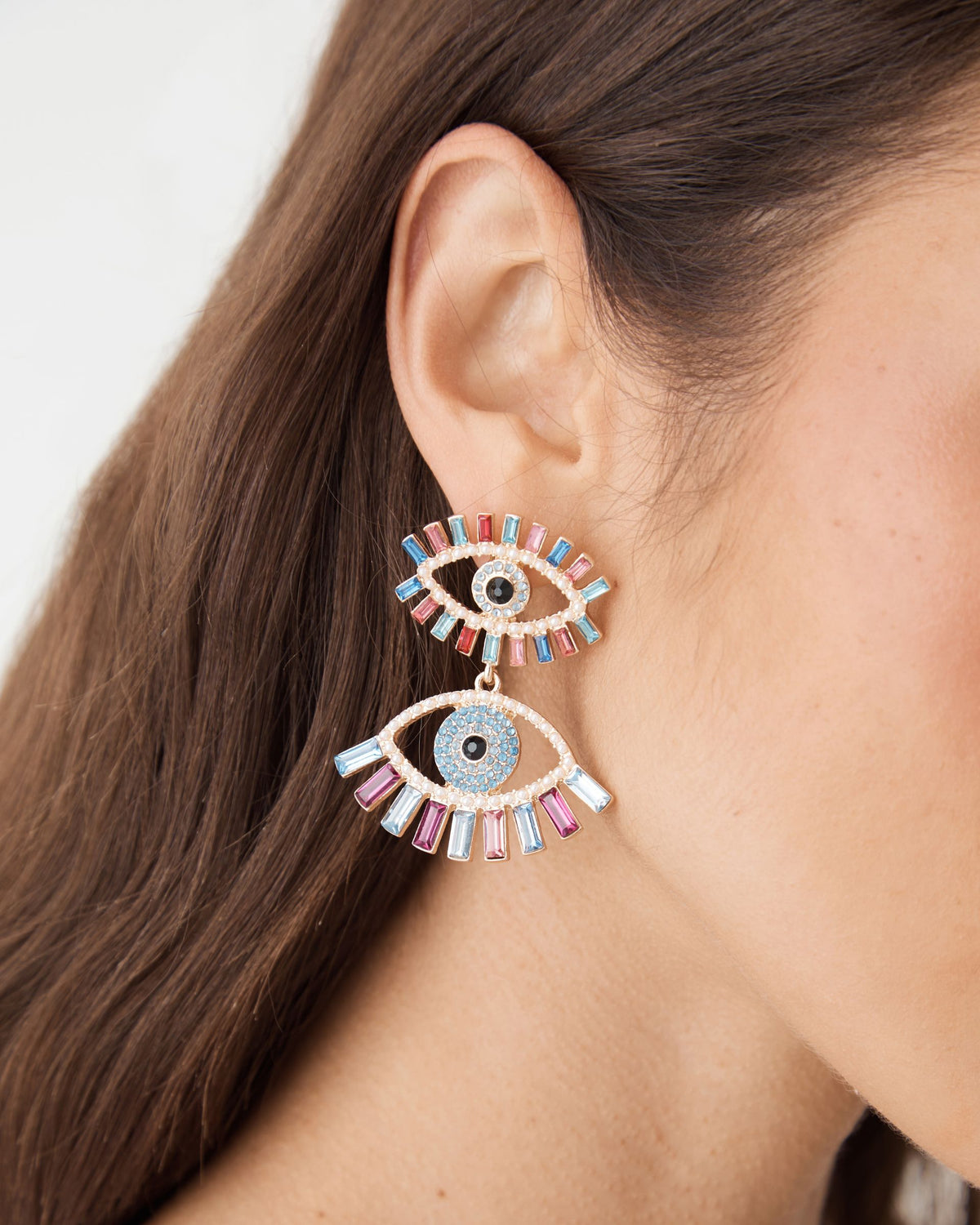 Close-up of Rainbow Eye Drop Earrings in rainbow, two-tier evil-eye drop with baguette stones, worn on ear