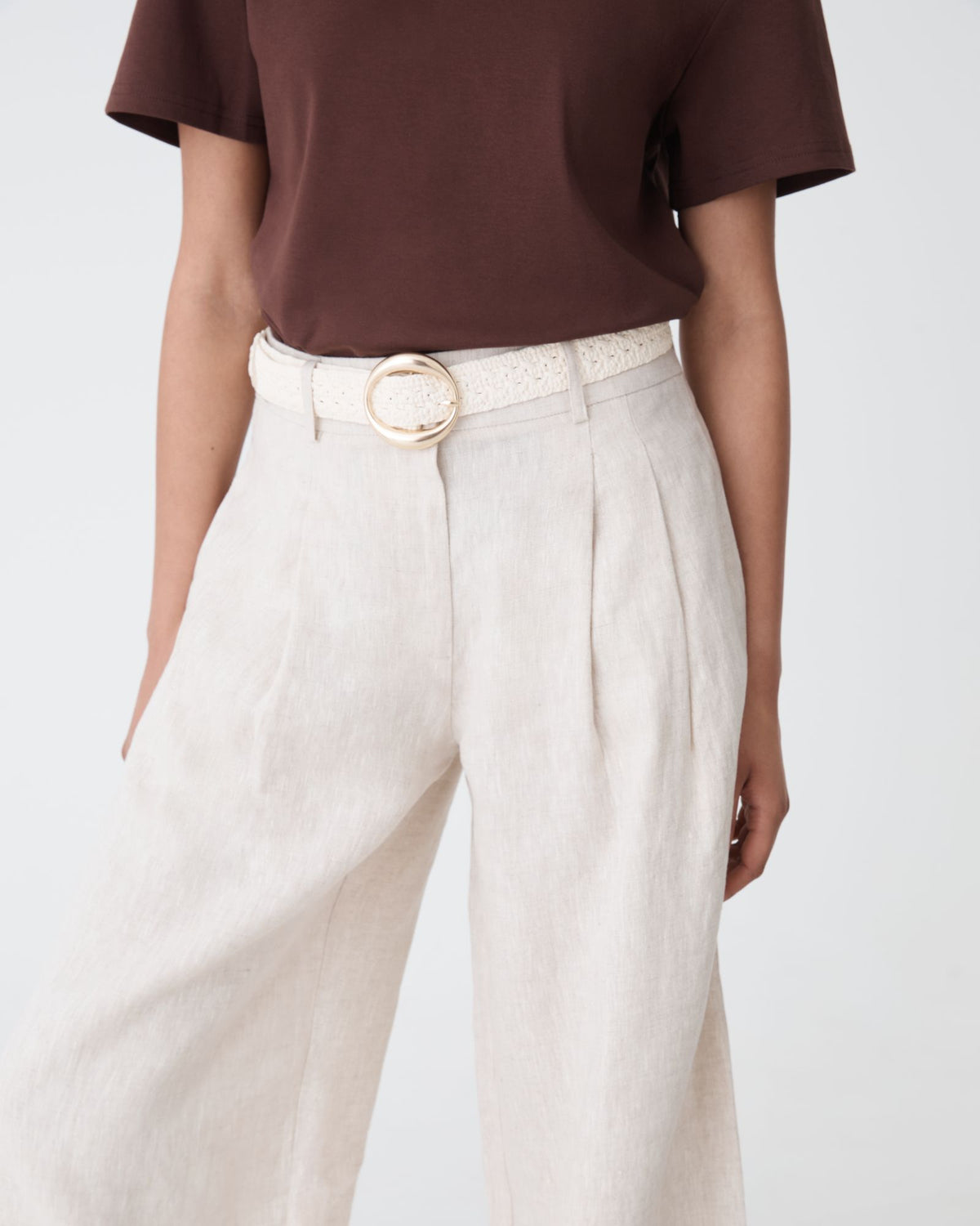 Elena Crochet Belt in ivory with round gold-tone buckle, worn at the waist with linen trousers and brown tee