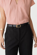 Rue Leather Belt in black worn at the waist of black trousers with a pink top, gold-tone D-shaped buckle