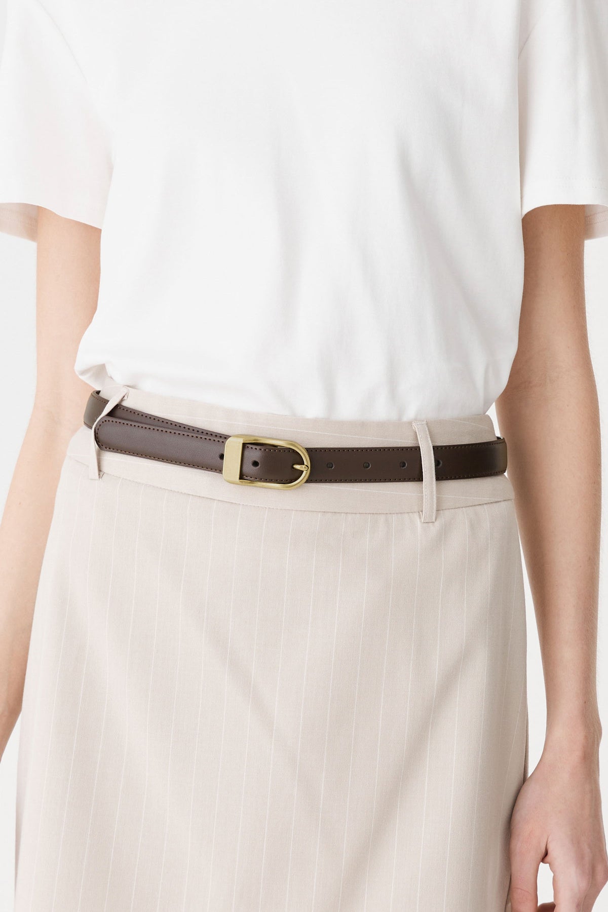 Close-up of the brushed gold-tone D-shaped buckle and rounded strap tip