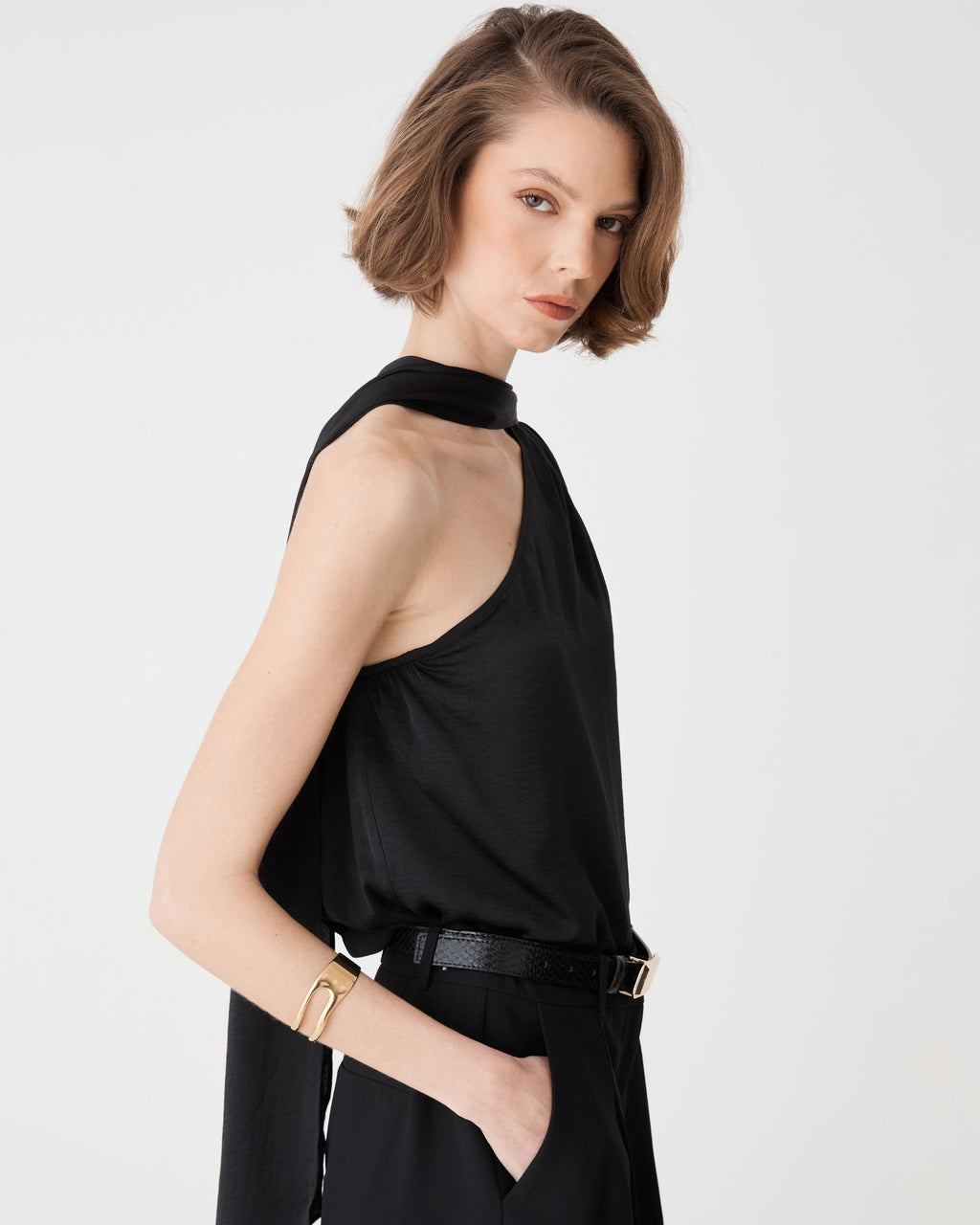 Side view of the black croc-effect belt worn over black trousers with a sleeveless top